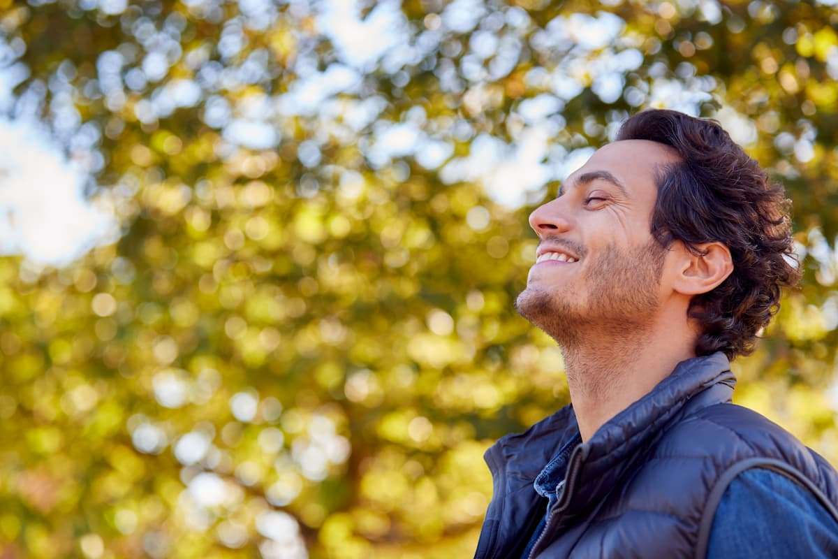 Man outdoors smiling and reflecting on his year, representing mindfulness and goal setting for 2026
